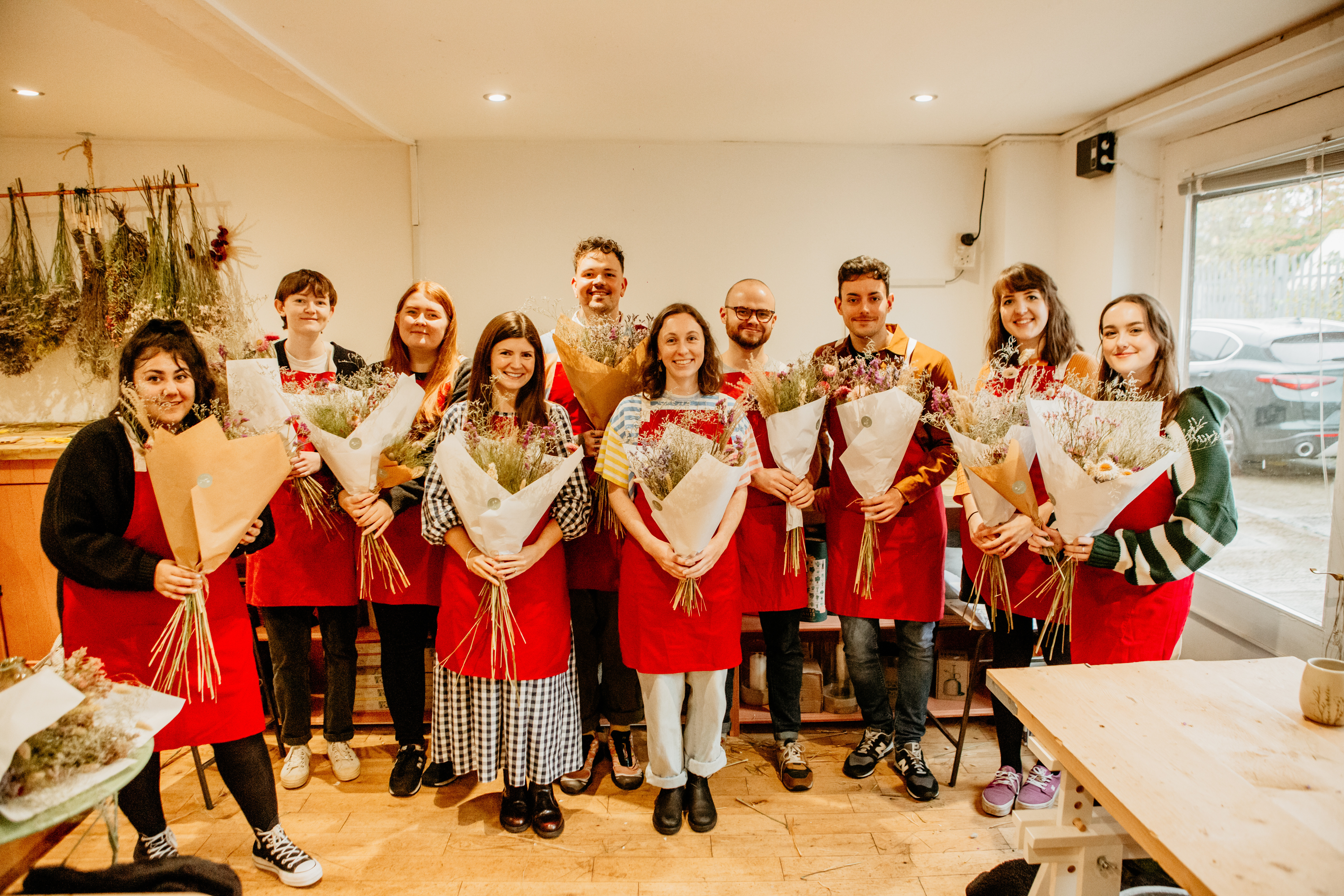 Young group of people in red aprons holding bunches of flowers